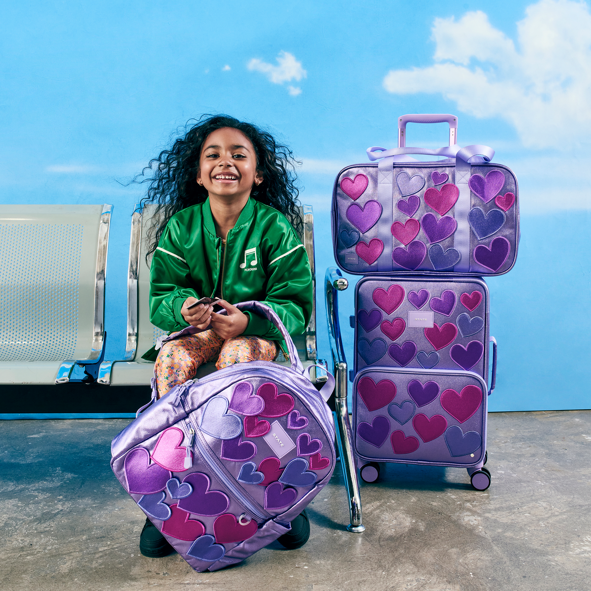 Girl sitting with STATE Bags 3d hearts bundle at the aiport