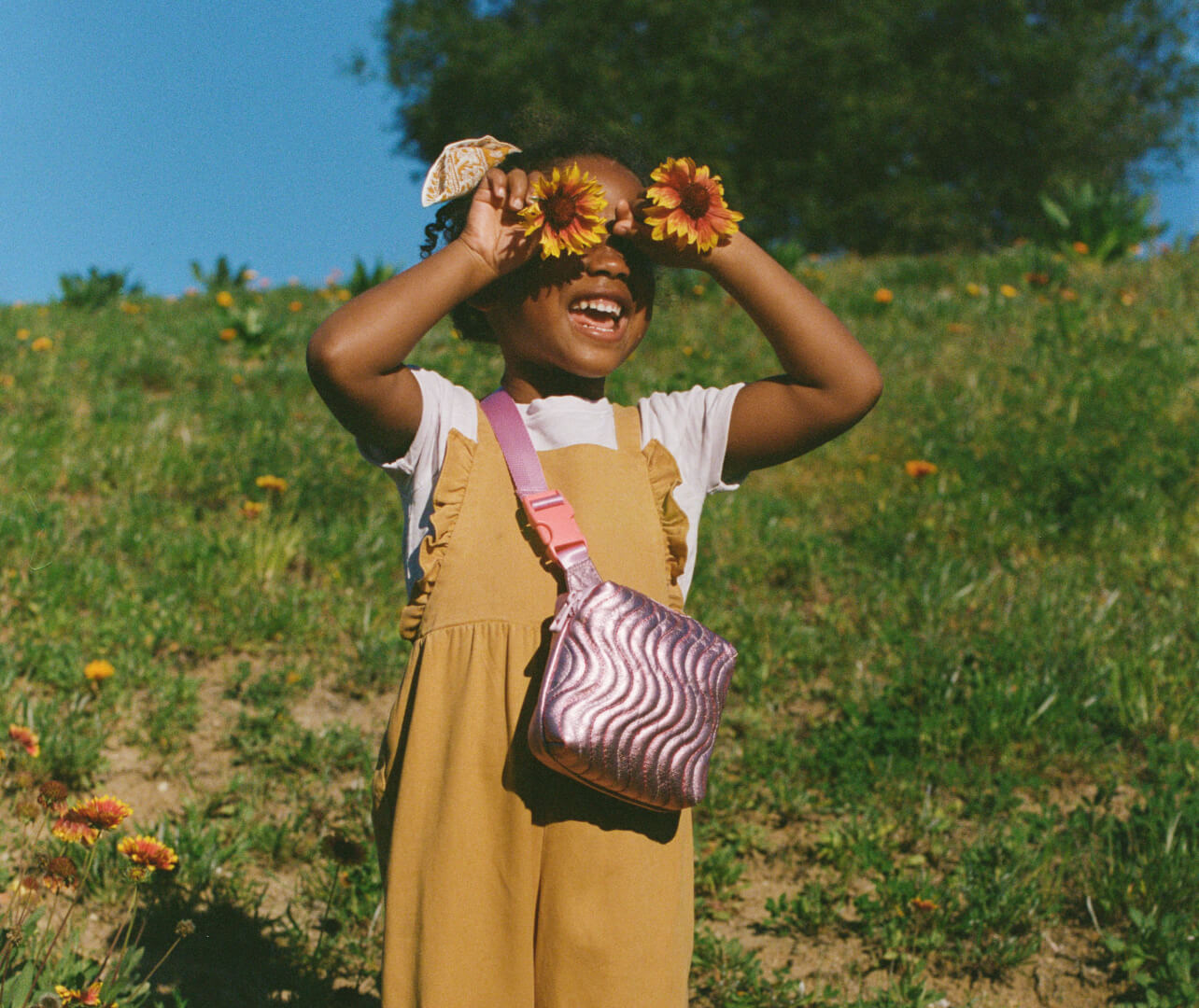Girl wearing pink fanny pack holding sunflowers