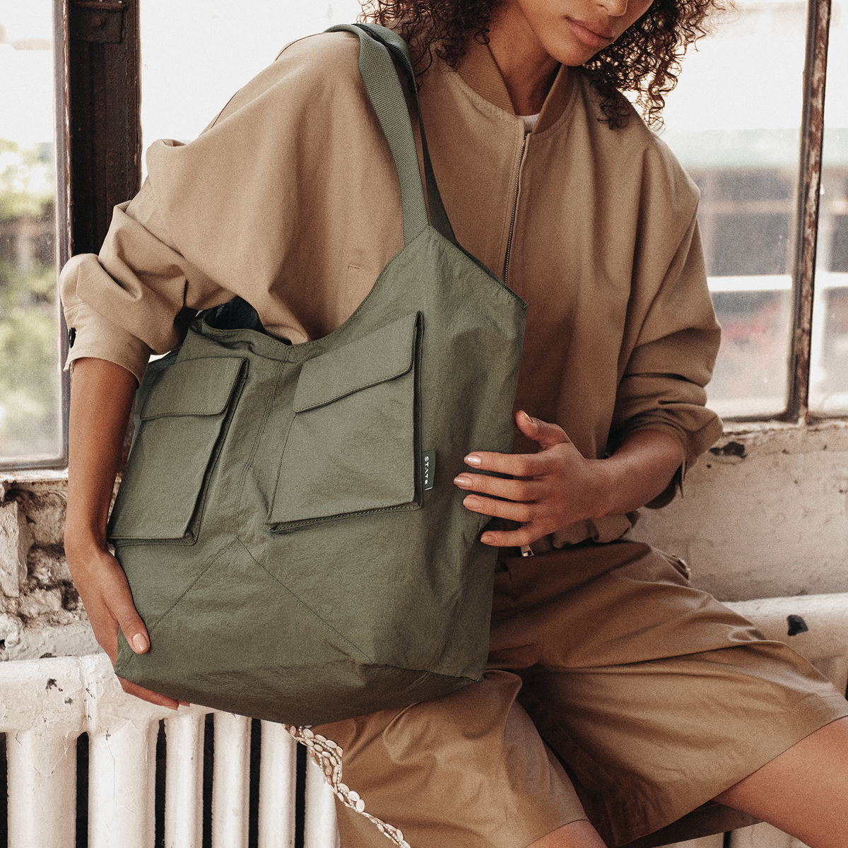 Image showing woman wearing STATE Bags Beverly Tote Crinkled Nylon Olive