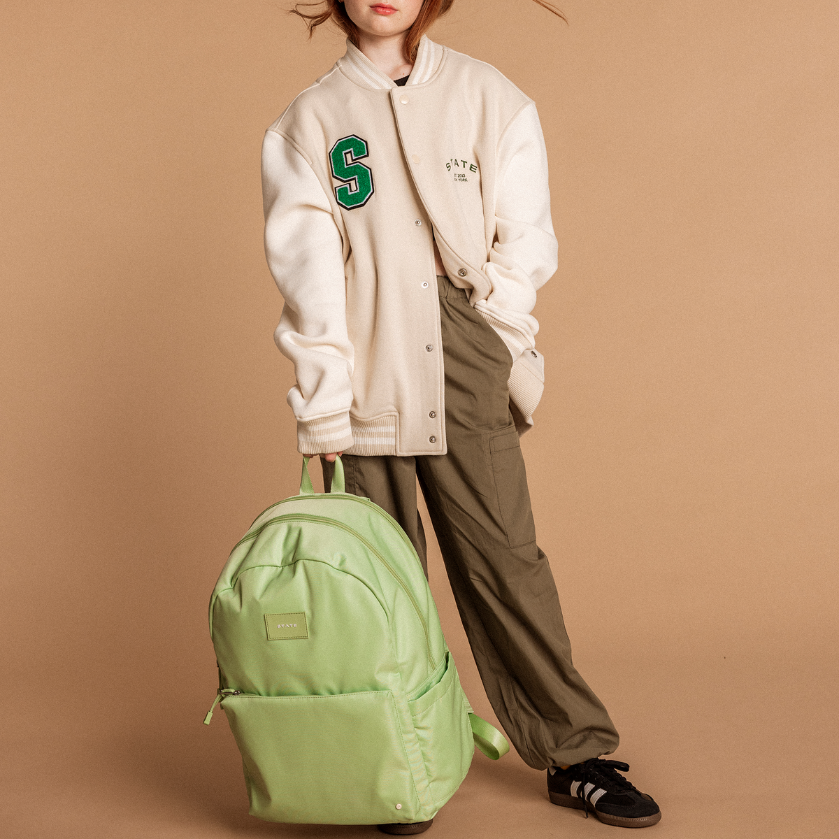 Girl holding STATE Bags Double Pocket Backpack Green