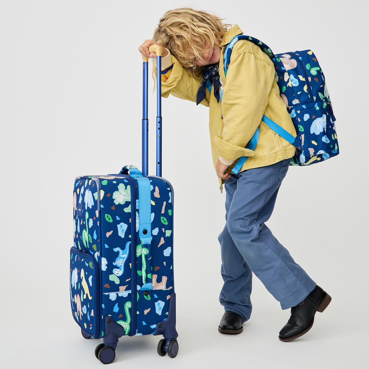boy holding STATE Bags Logan Carry-On Suitcase Dino Fossils
