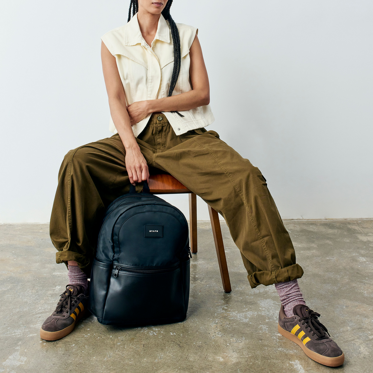 woman sitting on chair holding STATE Bags Evan's Double Pocket Black