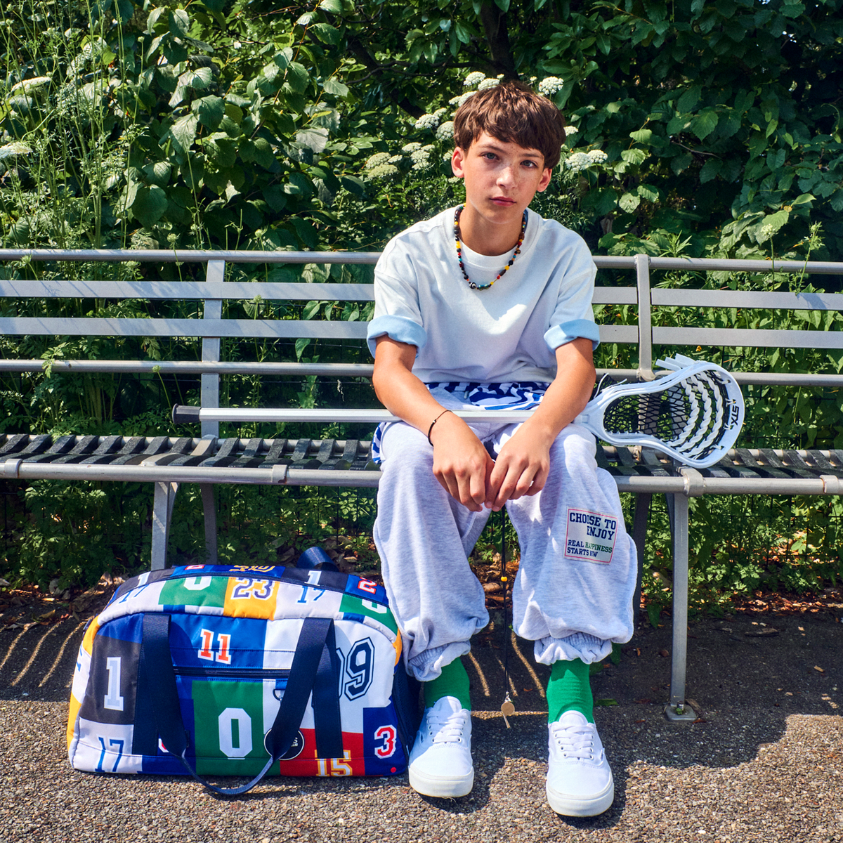 boy sitting on bench with STATE Fenway Sports Duffle Varsity Numbers
