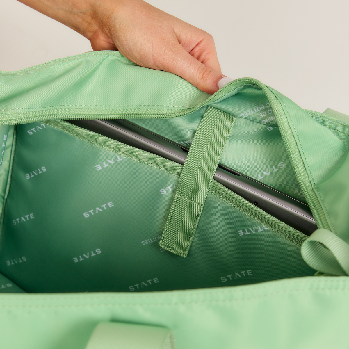 girl opening state bags graham tote green with laptop in it