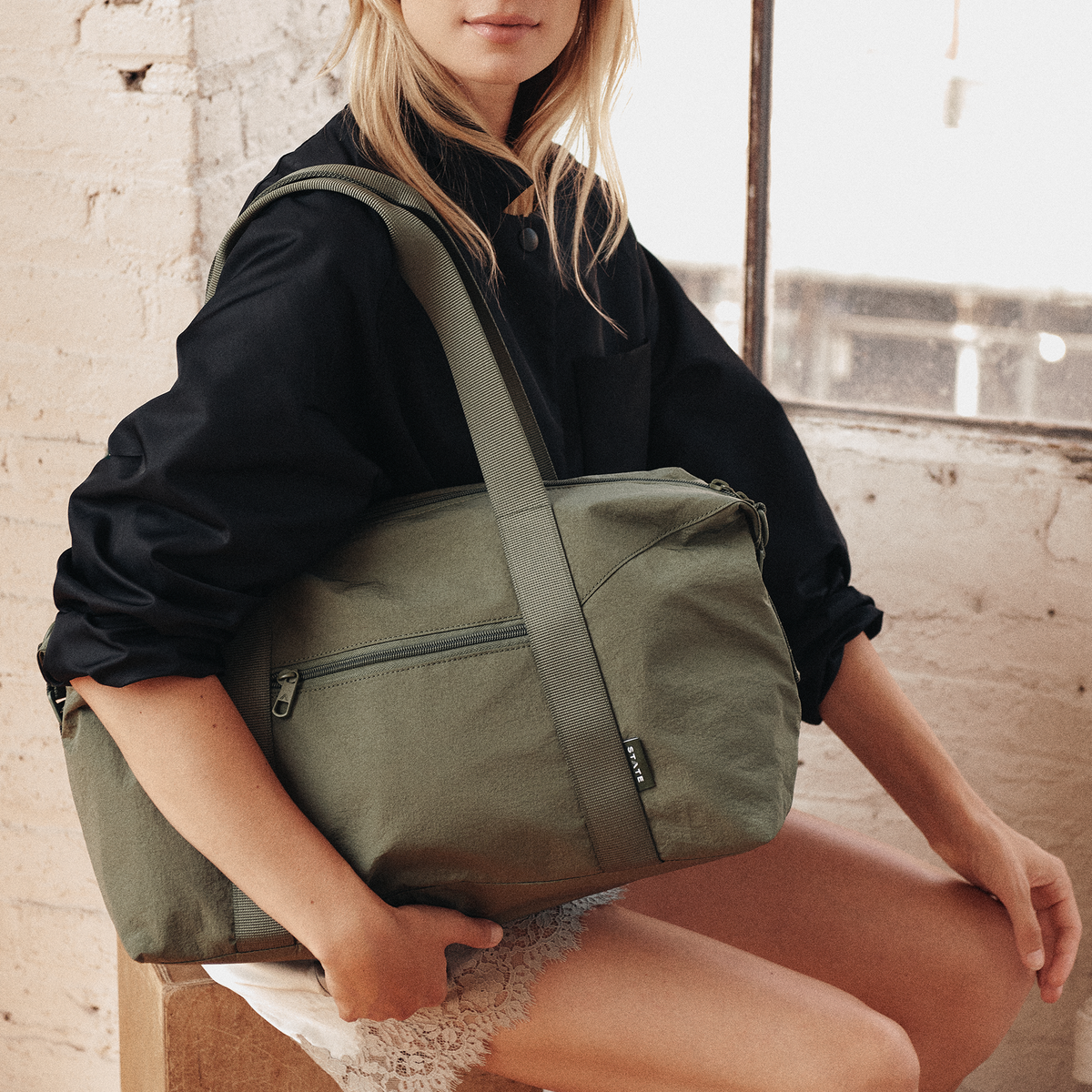 Woman wearing STATE Bags Harlow Carryall Crinkle Nylon Olive