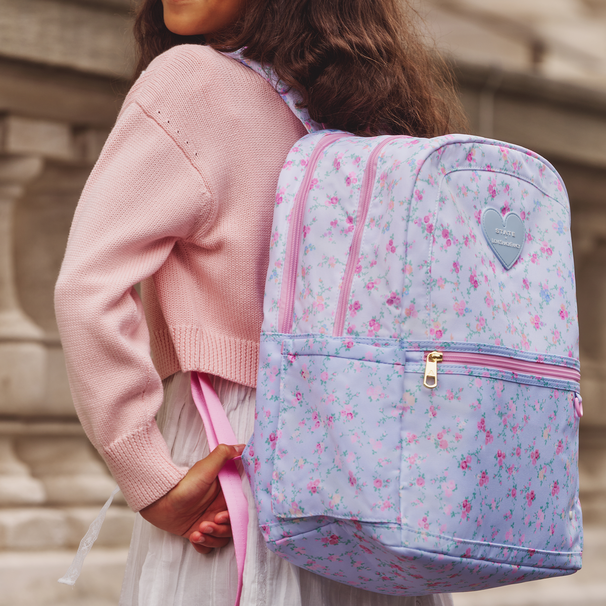 Girl wearing STATE x LoveShackFancy Kane Double Pocket Backpack Polyester Canvas Confetti Bloom / Wildflower Blue 