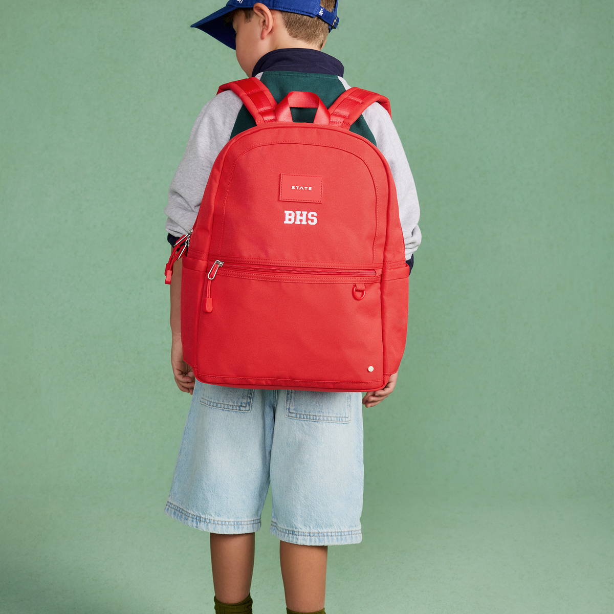 boy wearing kane backpack red