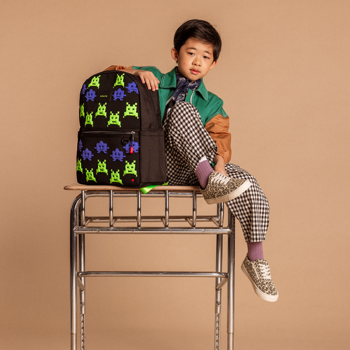 Boy sitting on desk with Kane Backpack Space Invaders