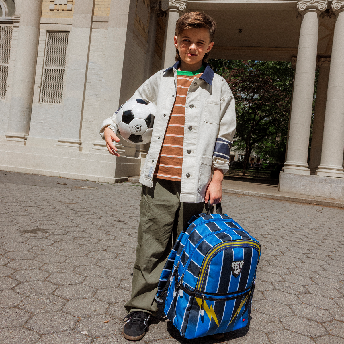 Boy holding State Bags Double Pocket Backpack Soccer Jersey