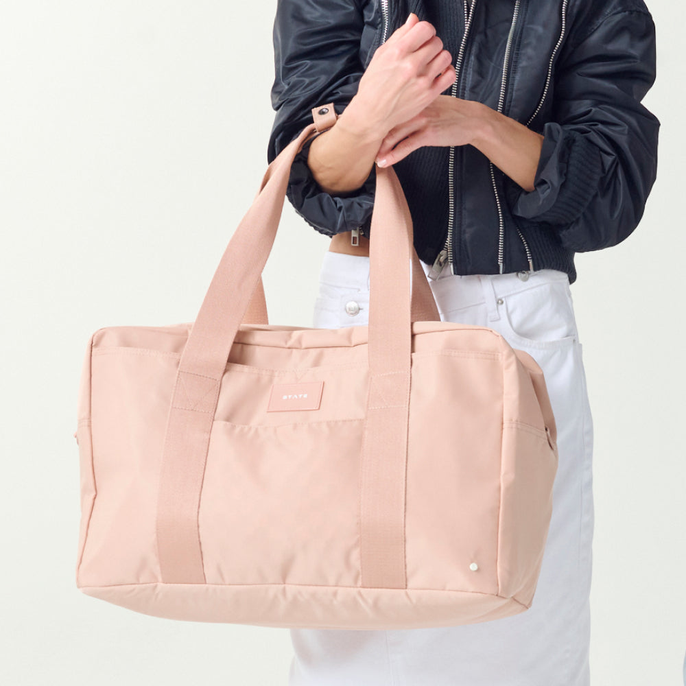 Womna holding STATE Bags Wellington Weekender Latte 