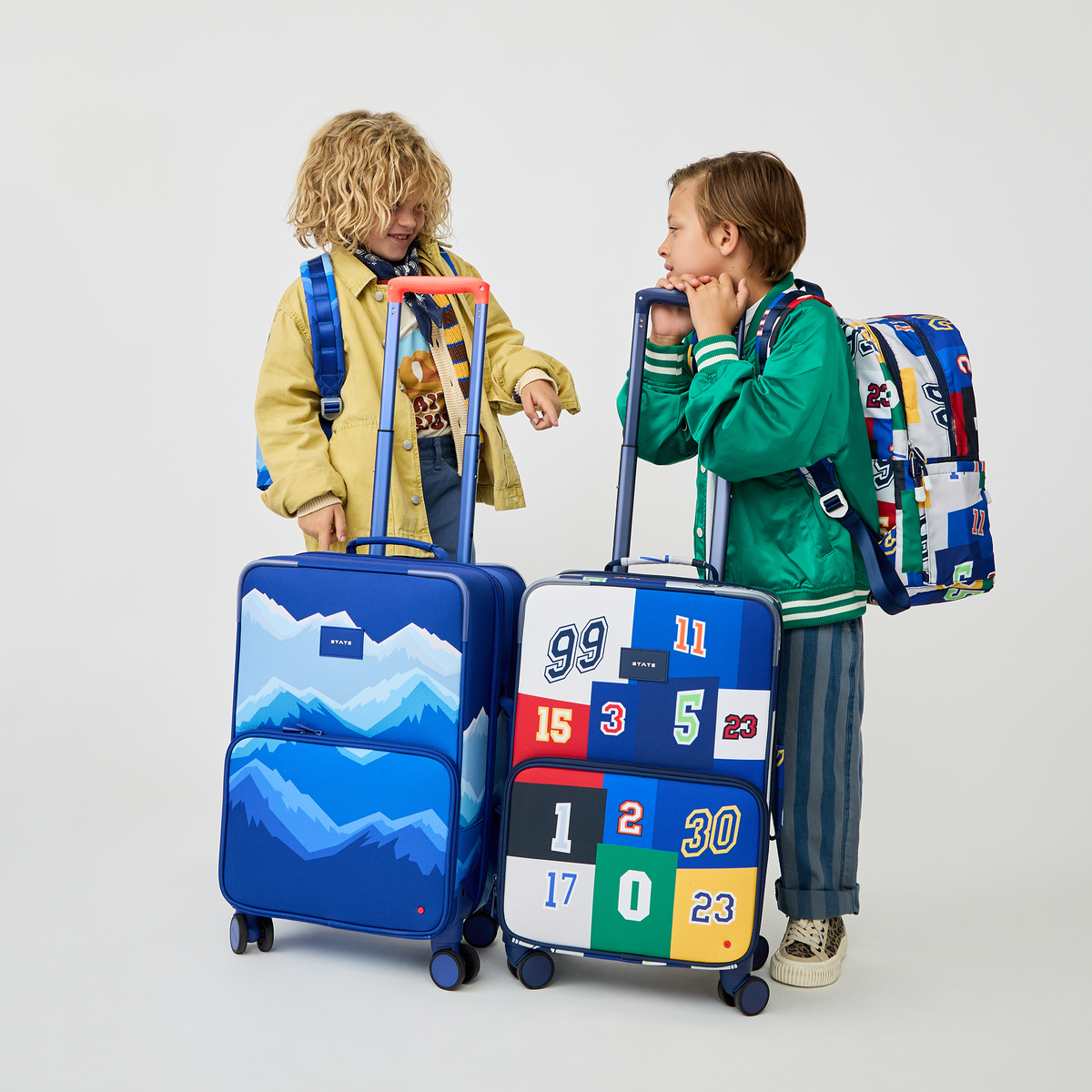 boy holding STATE Bags Logan Carry-On Suitcase Varisty Numbers