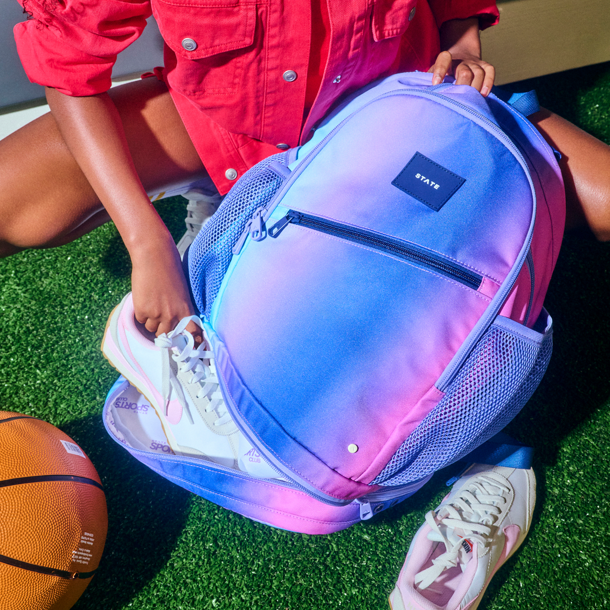 Girl putting shoes in Ozzie Ball Backpack Blue/Pink Gradient