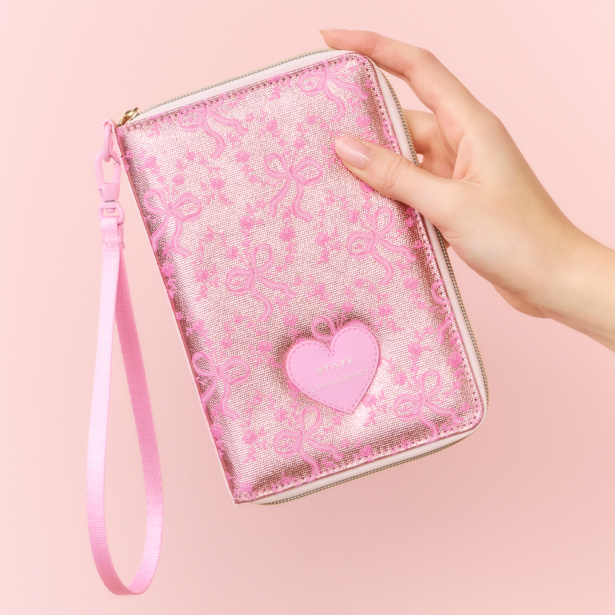 Woman holding STATE x LoveShackFancy Passport Holder Metallic Pink Vanilla 