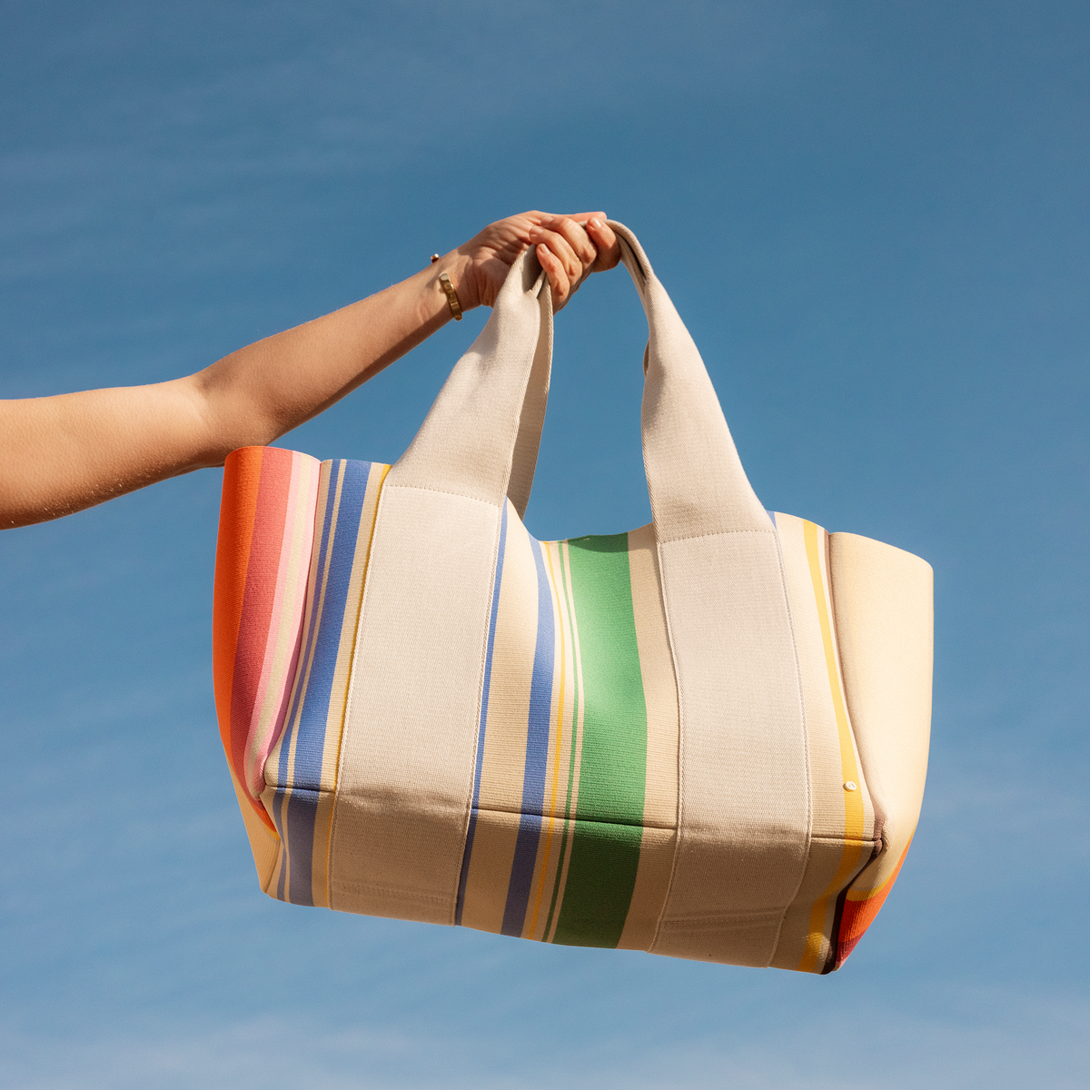 woman holding STATE Bags Wellington Cabana Tote Rainbow Stripe 