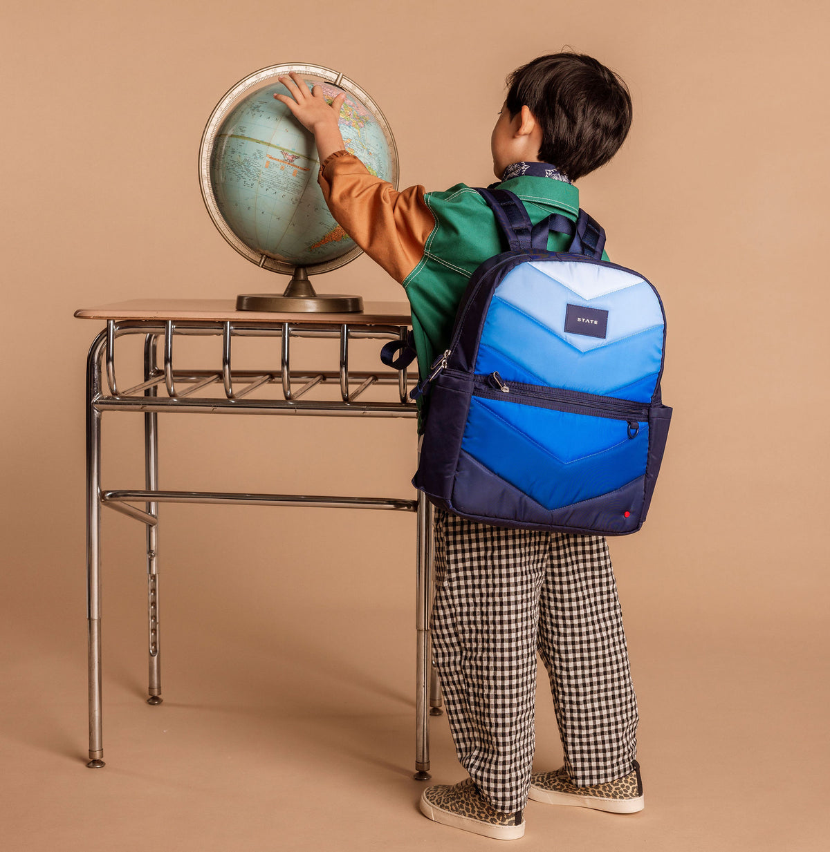 Boy wearing navy backpack playing with globe