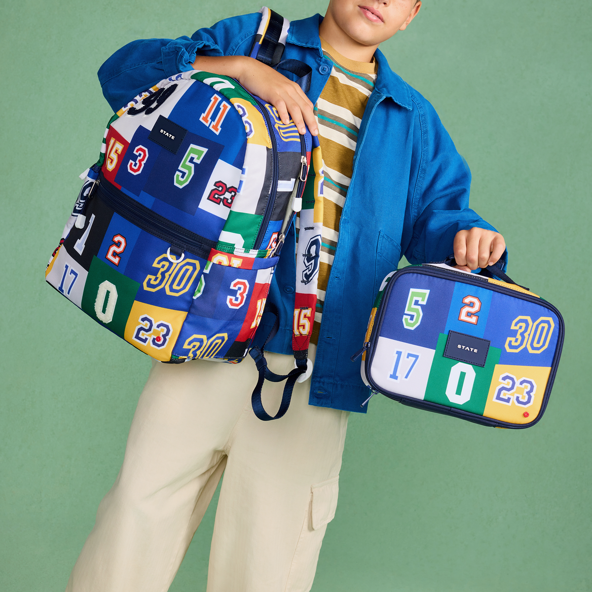 Boy holding STATE Bags Kane Double Pocket Backpack Varsity Numbers