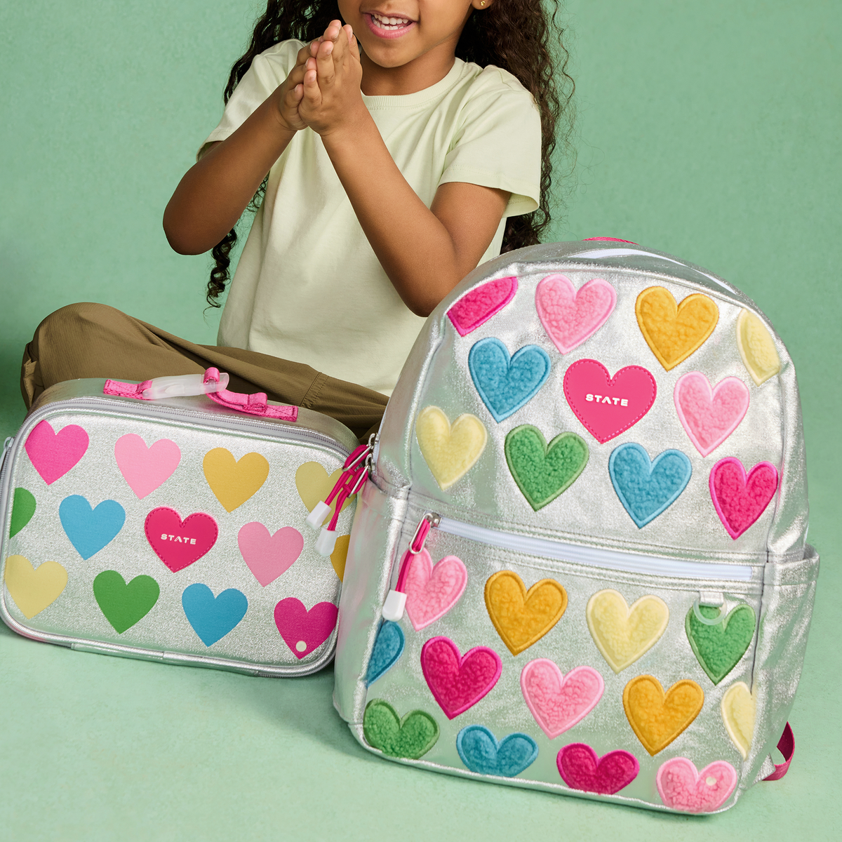 girl sitting with STATE Bags Kane Backpack Happy Fuzzy Hearts