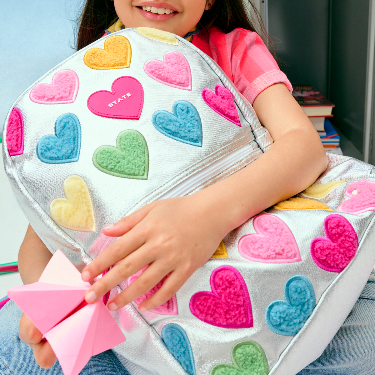 girl sitting with STATE Bags Kane Backpack Happy Fuzzy Hearts