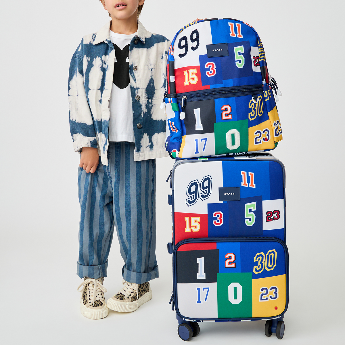 boy holding STATE Bags Logan Carry-On Suitcase Varisty Numbers