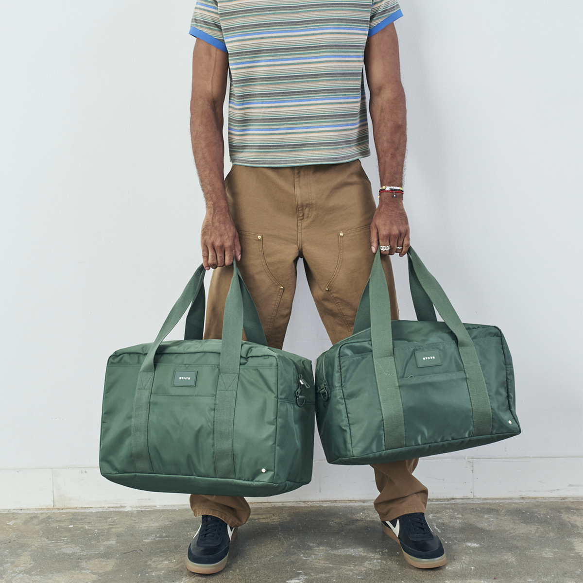 man holding state bags wellington weekender medium and regular sized wellington weekender in olive